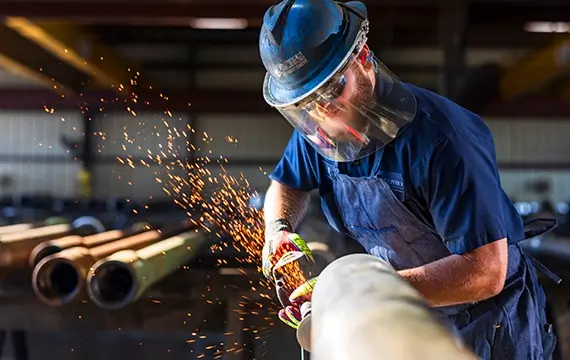 A Workstrings warehouse working cutting a pipe