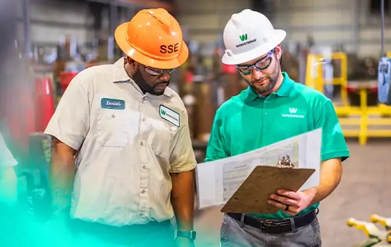 Workstring warehouse workers looking for a large spec sheet together 