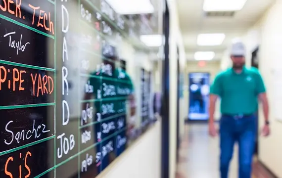 A Workstrings worker walking by a safety board 