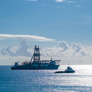 A deepwater drilling vessel and smaller support ship cruising through the Gulf of Mexico