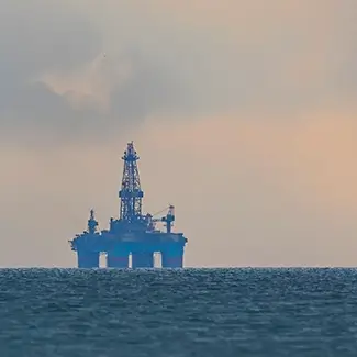 An oil rig on the horizon in the Gulf of Mexico with a hazy sunset