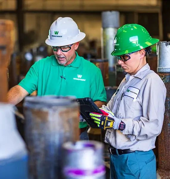 Two Workstrings workers looking over the conditioning of pipes and making notes on where reparis are needed