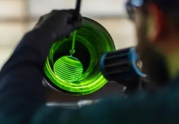 A Workstrings worker examining the interior of a pipe with a mirror and green light