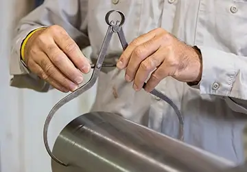 A Workstrings worker using a clamp to measure the width of a drill string