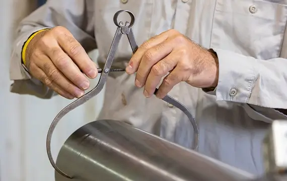 A Workstrings worker using a clamp to measure the width of a drill string