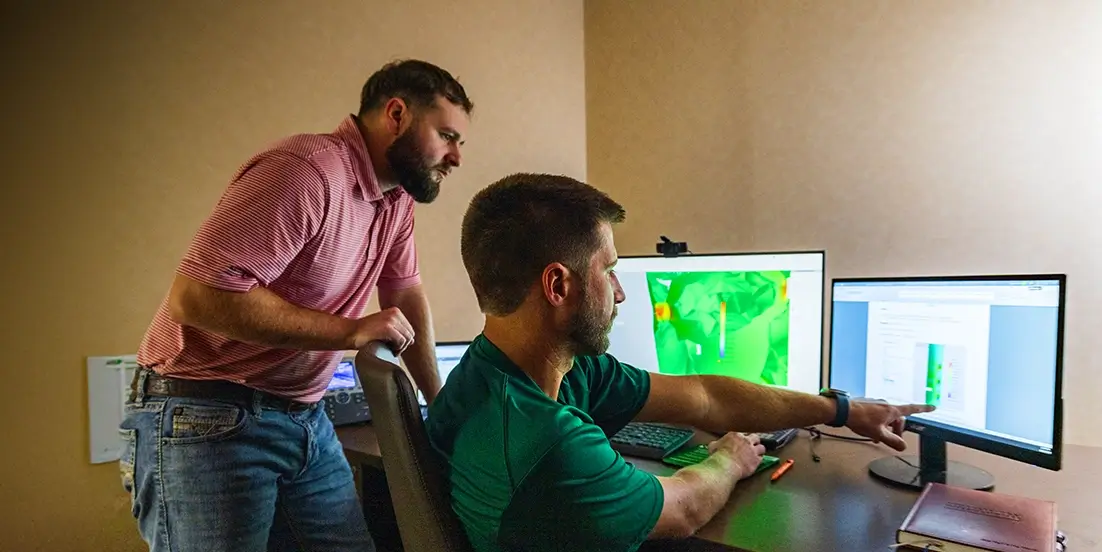 Two Workstrings engineers looking at readouts on a monitor at a desk