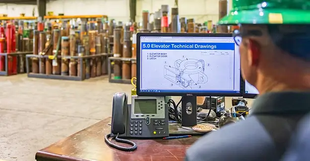 A Workstrings engineer looking over elevator technical drawings in a warehouse