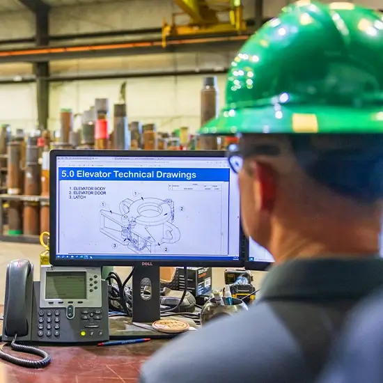 A Workstrings engineer looking over elevator technical drawings in a warehouse