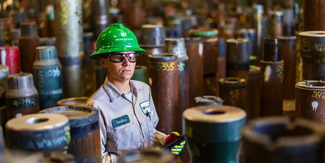 A female Workstrings worker taking inventory of drill pipes
