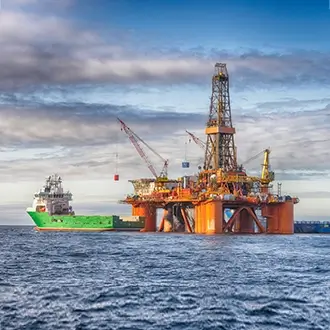A green oil tanker docking at an oil platform in the gulf