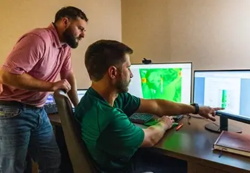 Two Workstrings engineers looking at readouts on a monitor at a desk